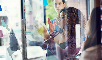 Buy stock photo Cropped shot of a group of young designers brainstorming with notes on a glass wall in an office