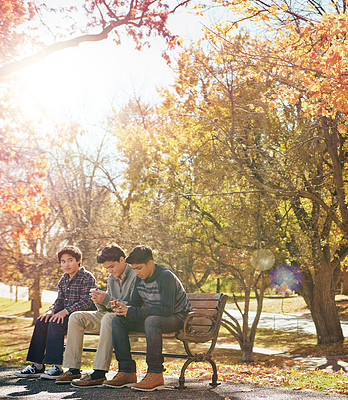 Buy stock photo Shot of a group of friends hanging out together outside on an autumn day