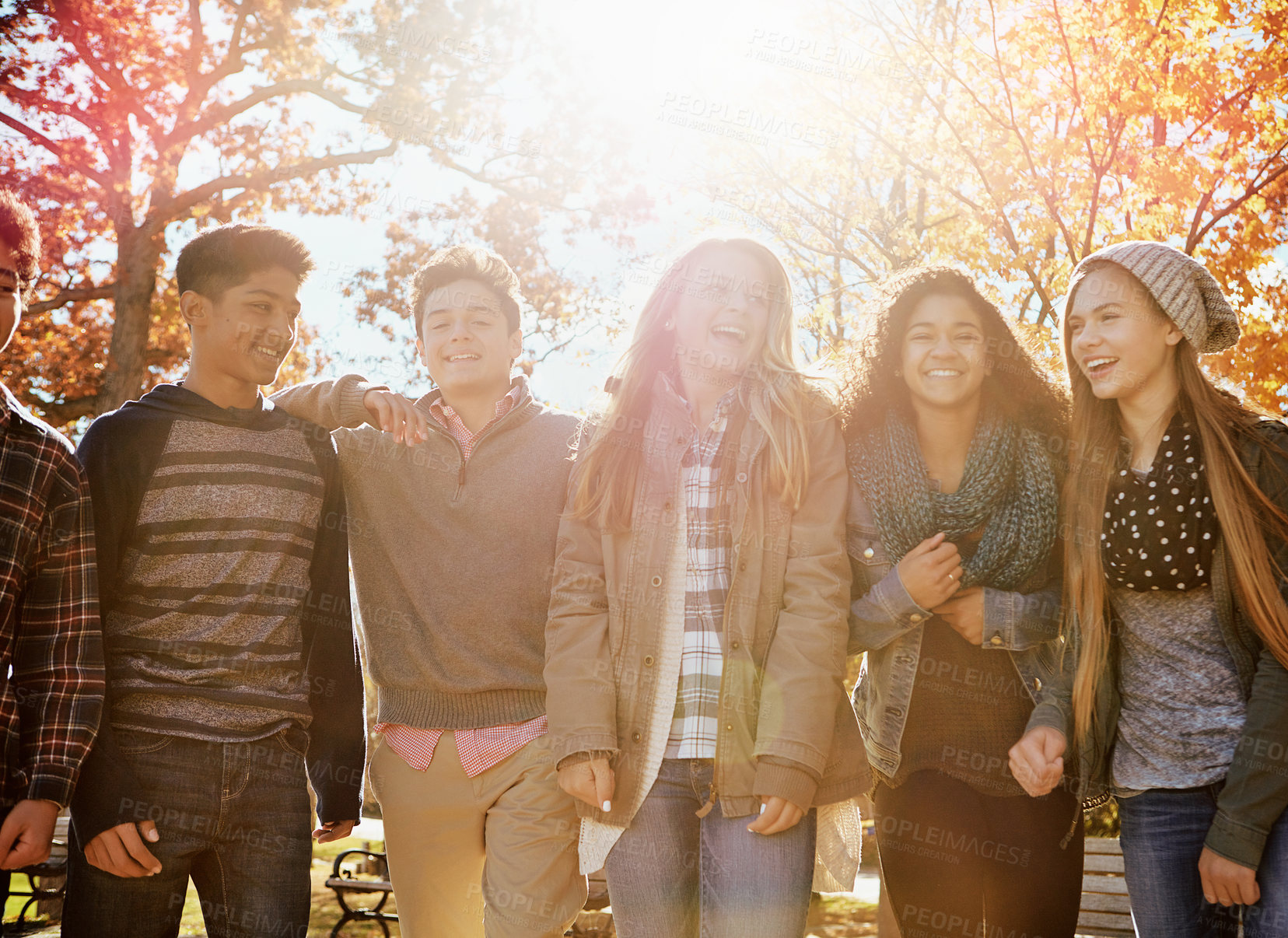 Buy stock photo Teenager, friends and laugh outdoor with autumn weather, funny conversation and bonding together. Portrait, flare or happy children in park with fall season, weekend hangout and humor for discussion.