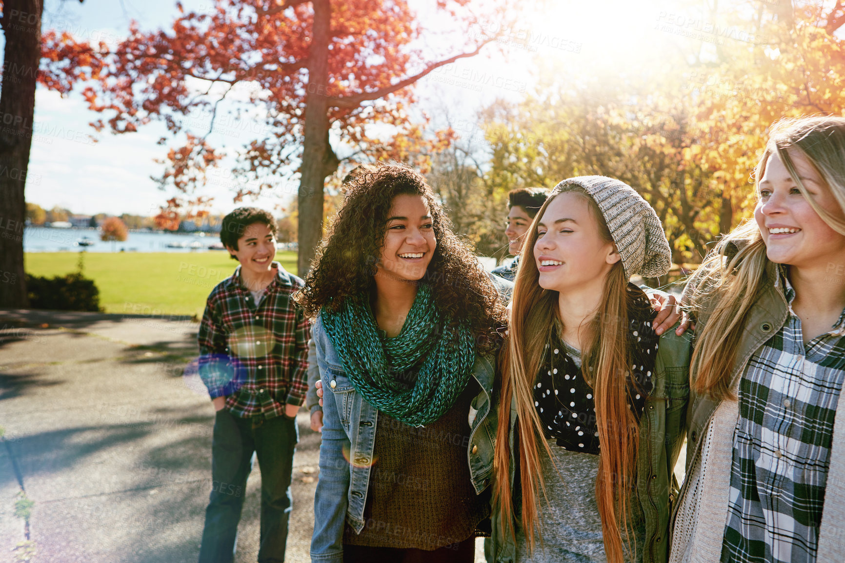 Buy stock photo Teenage group, laughing and walking in park for fall break, bonding together and sunshine. Happy, friends or girls with hug outdoor for holiday reunion, weekend stroll or funny conversation in nature