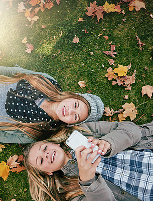 Buy stock photo High angle shot of two happy teenagers relaxing together on the grass outside