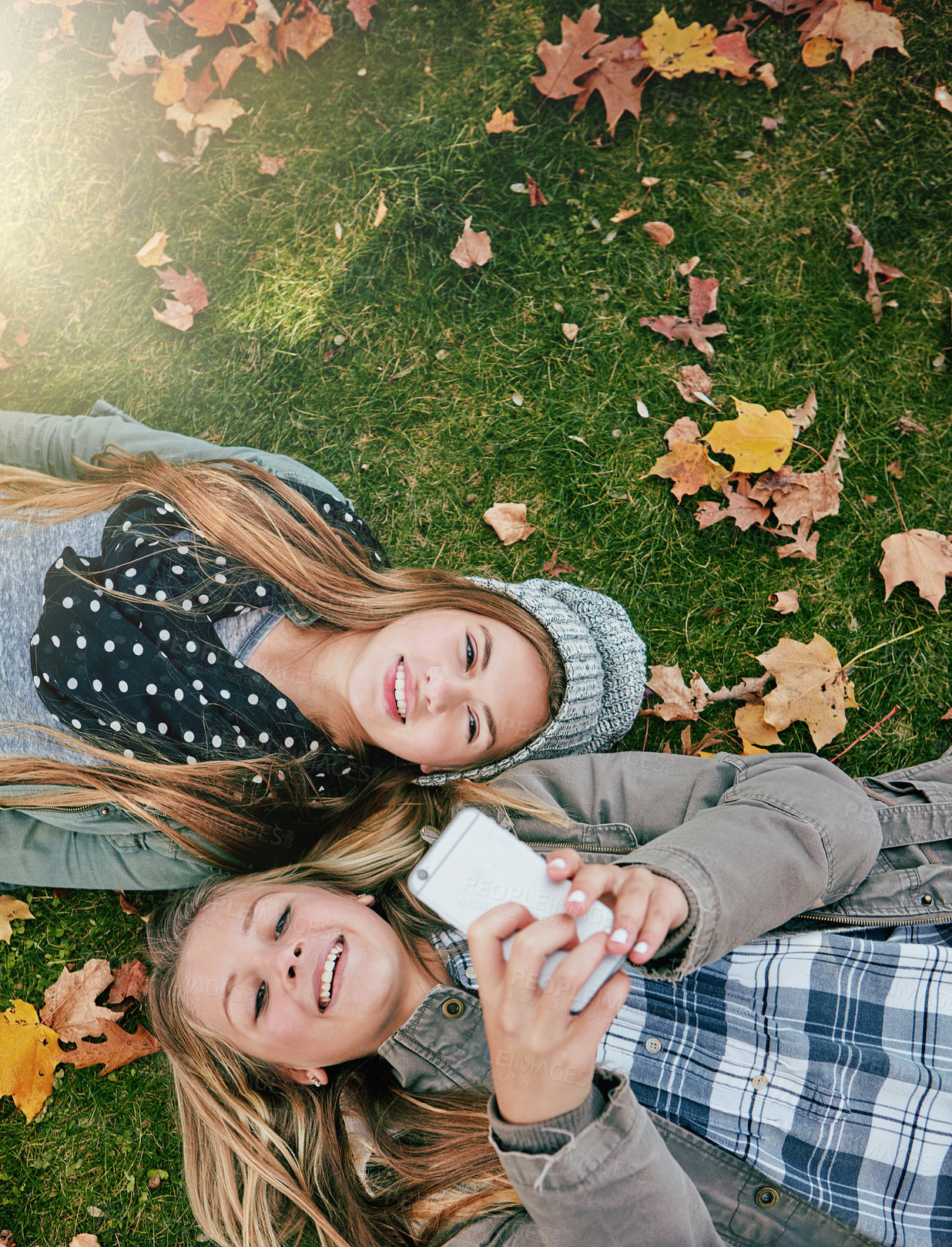 Buy stock photo High angle shot of two happy teenagers relaxing together on the grass outside