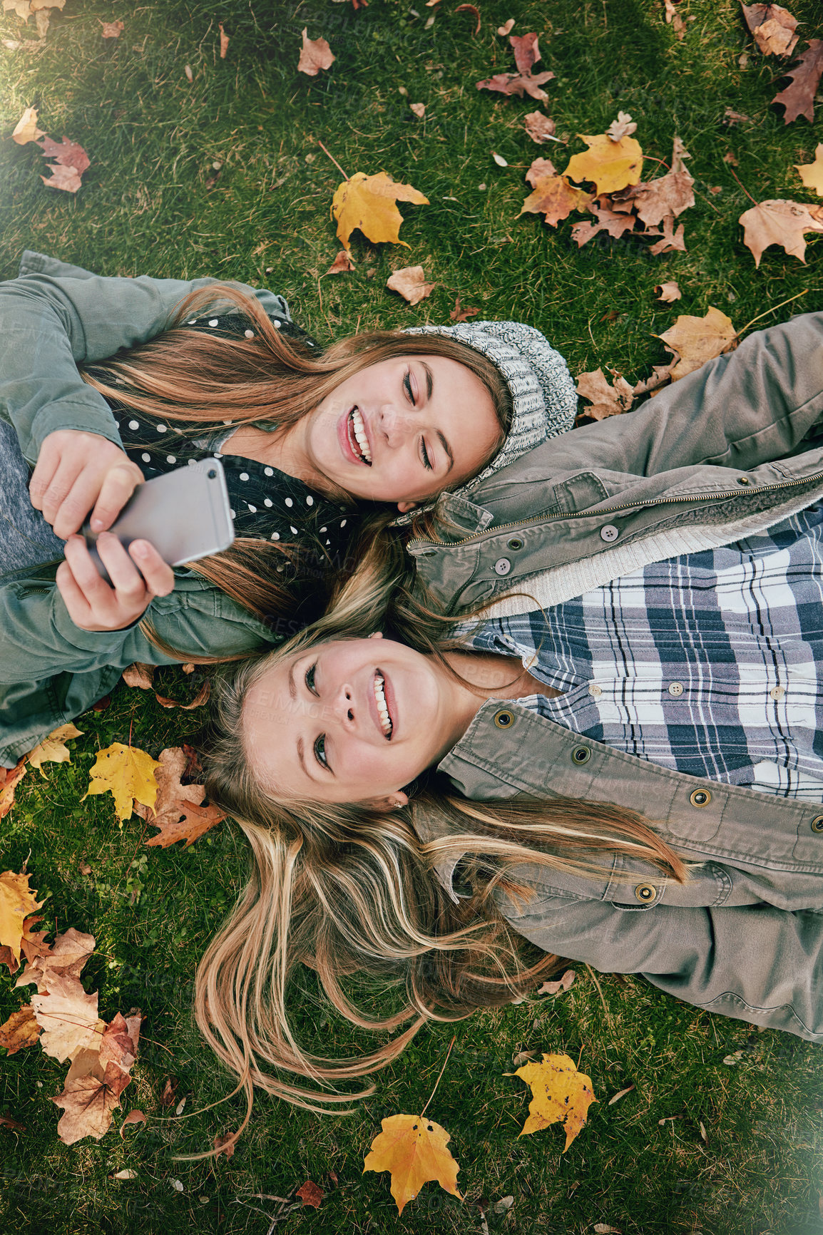 Buy stock photo High angle shot of two happy teenagers relaxing together on the grass outside