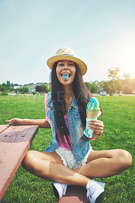 Buy stock photo Portrait of an attractive young woman enjoying an ice cream in the park