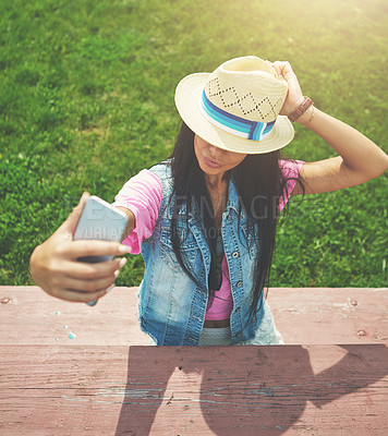 Buy stock photo Shot of an attractive young woman taking selfies while spending a day in the park