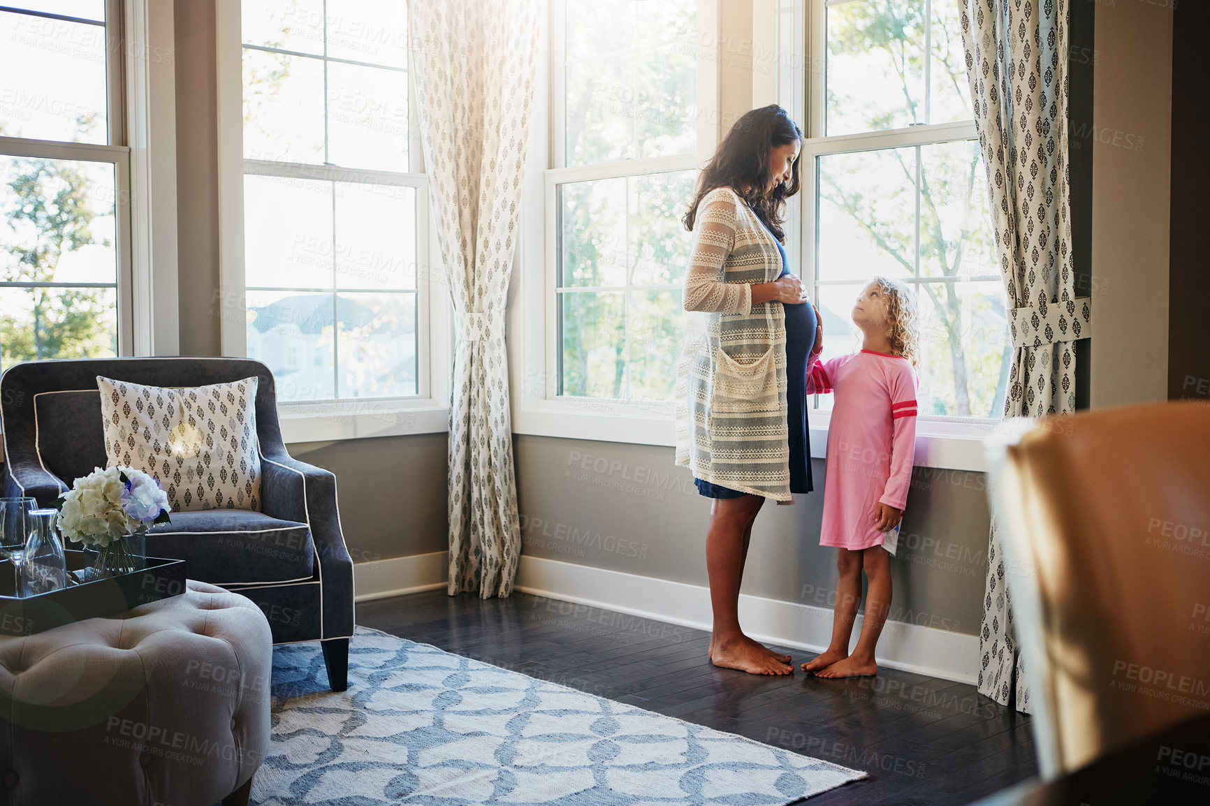 Buy stock photo Shot of a pregnant woman bonding with her little daughter at home