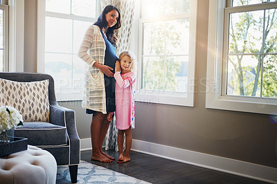 Buy stock photo Shot of a little girl pressing her ear to her mother's pregnant stomach at home