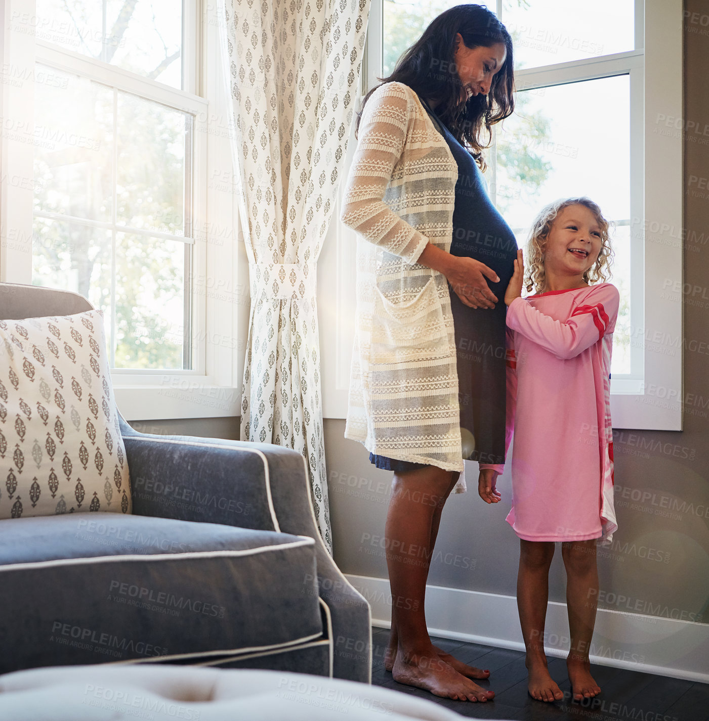 Buy stock photo Shot of a pregnant woman bonding with her little daughter at home