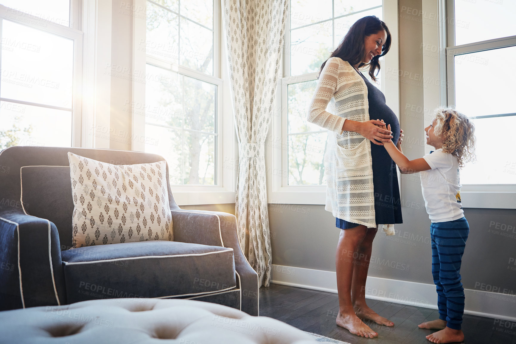 Buy stock photo Shot of a pregnant woman bonding with her little son at home