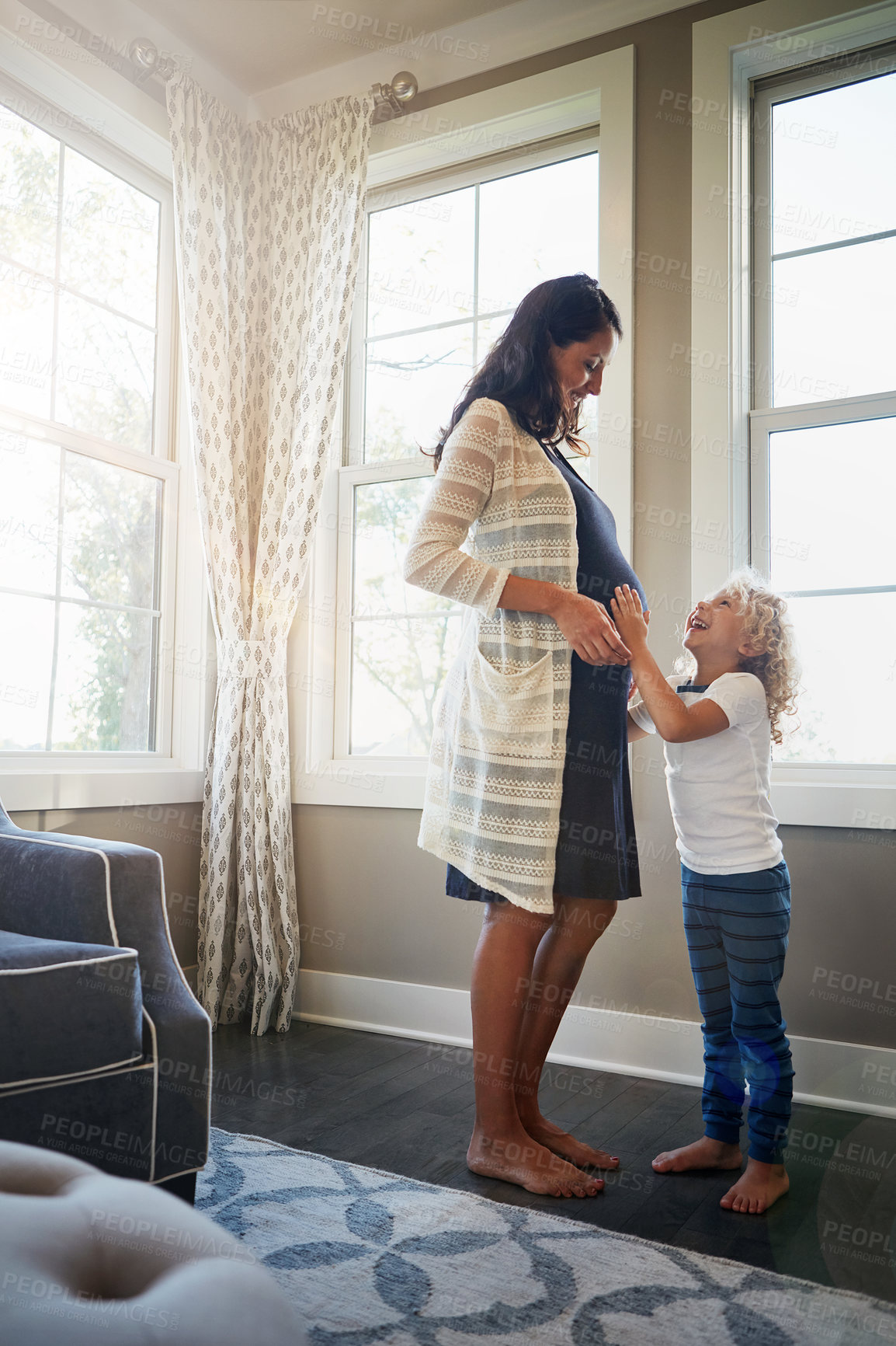 Buy stock photo Shot of a pregnant woman bonding with her little son at home