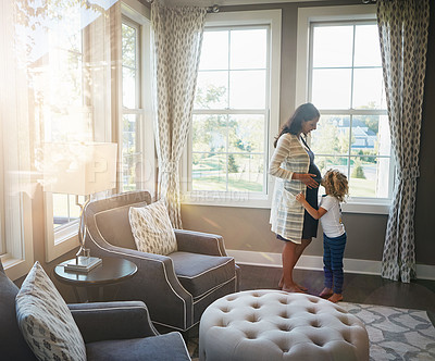 Buy stock photo Shot of a little boy kissing his mother's pregnant stomach at home