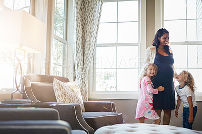 Buy stock photo Shot of a pregnant woman bonding with her little children at home