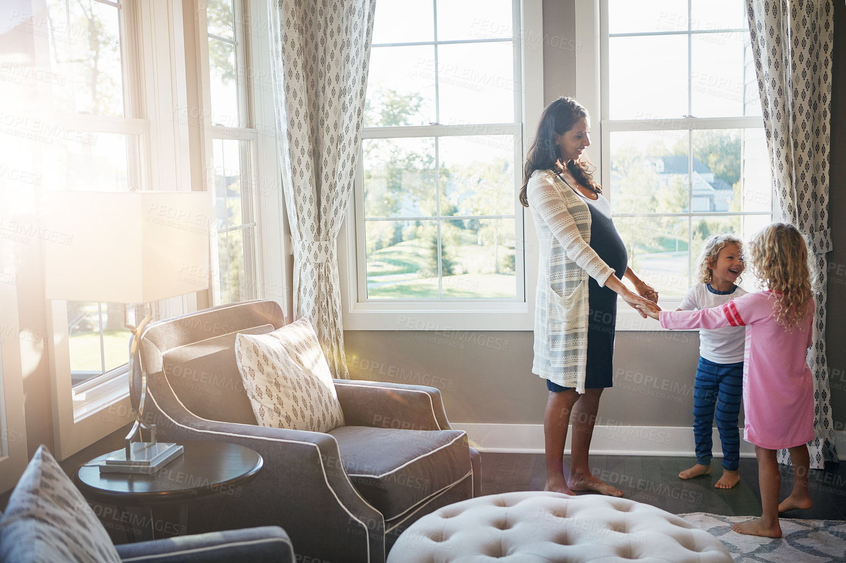 Buy stock photo Shot of a pregnant woman bonding with her little children at home