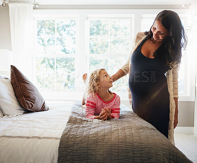 Buy stock photo Shot of a pregnant woman bonding with her little daughter at home