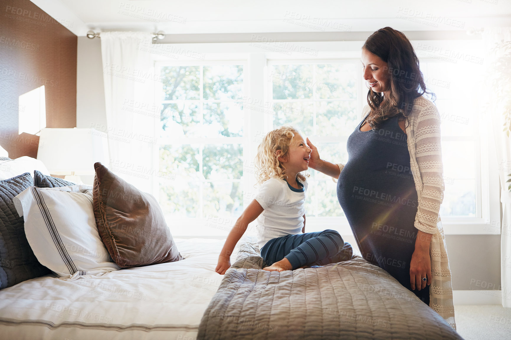 Buy stock photo Shot of a pregnant woman bonding with her little son at home