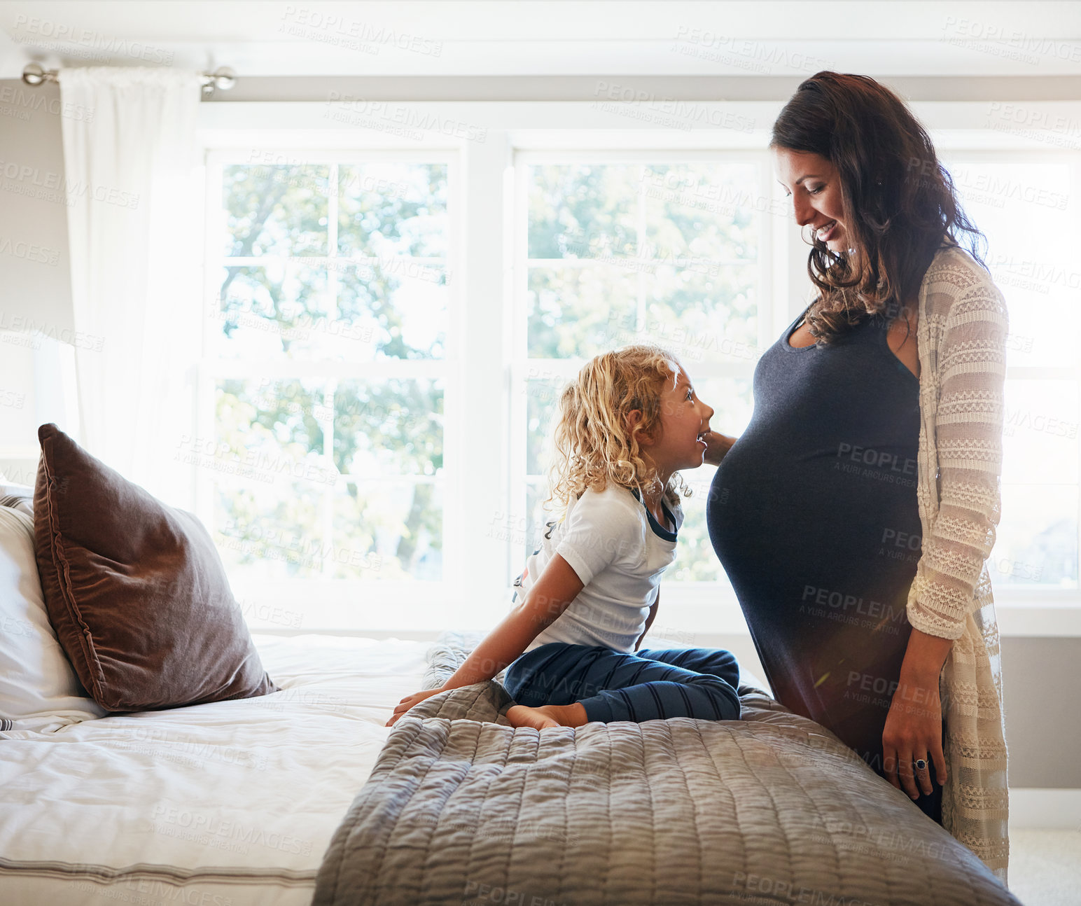 Buy stock photo Shot of a pregnant woman bonding with her little son at home