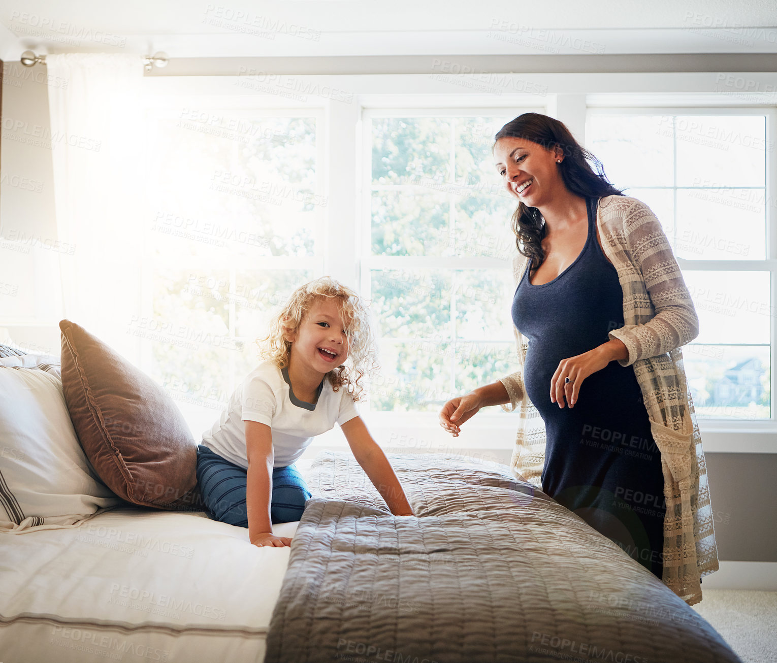 Buy stock photo Shot of a pregnant woman bonding with her little son at home