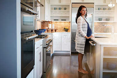 Buy stock photo Shot of a pregnant woman standing in her kitchen at home