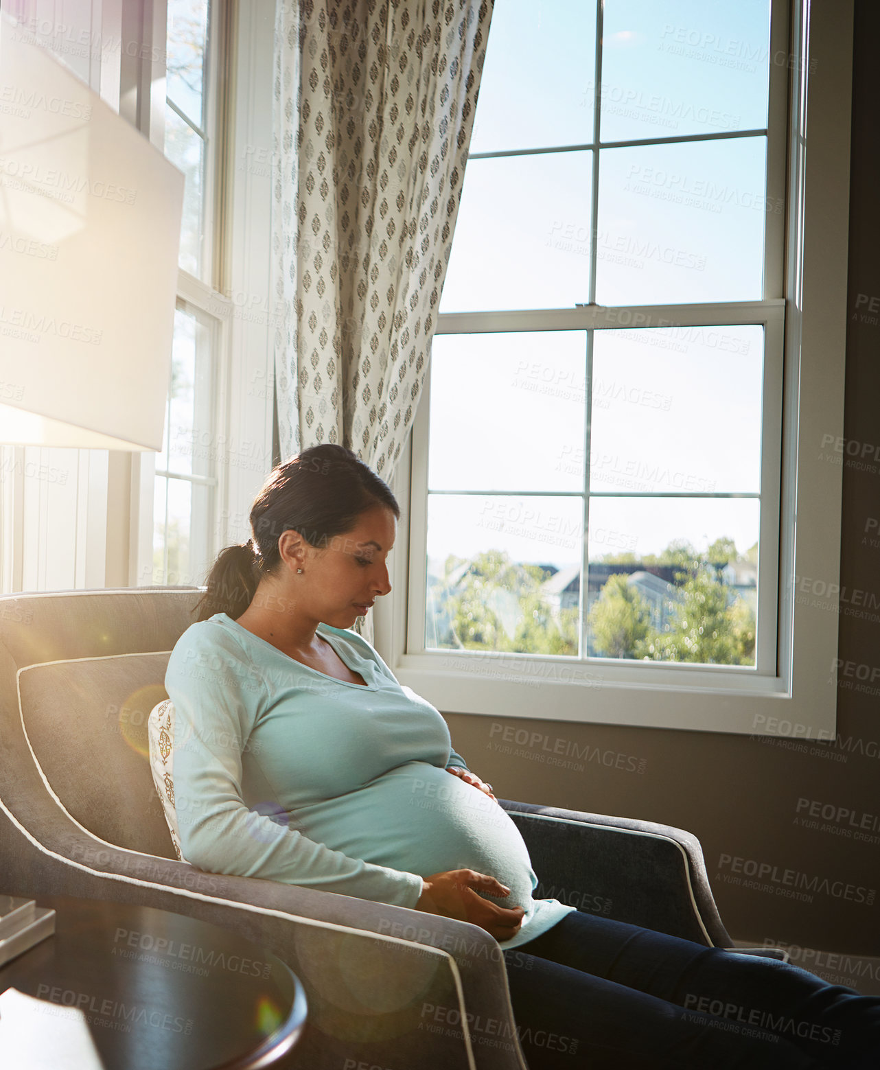 Buy stock photo Cropped shot of a pregnant woman sitting in her living room by herself