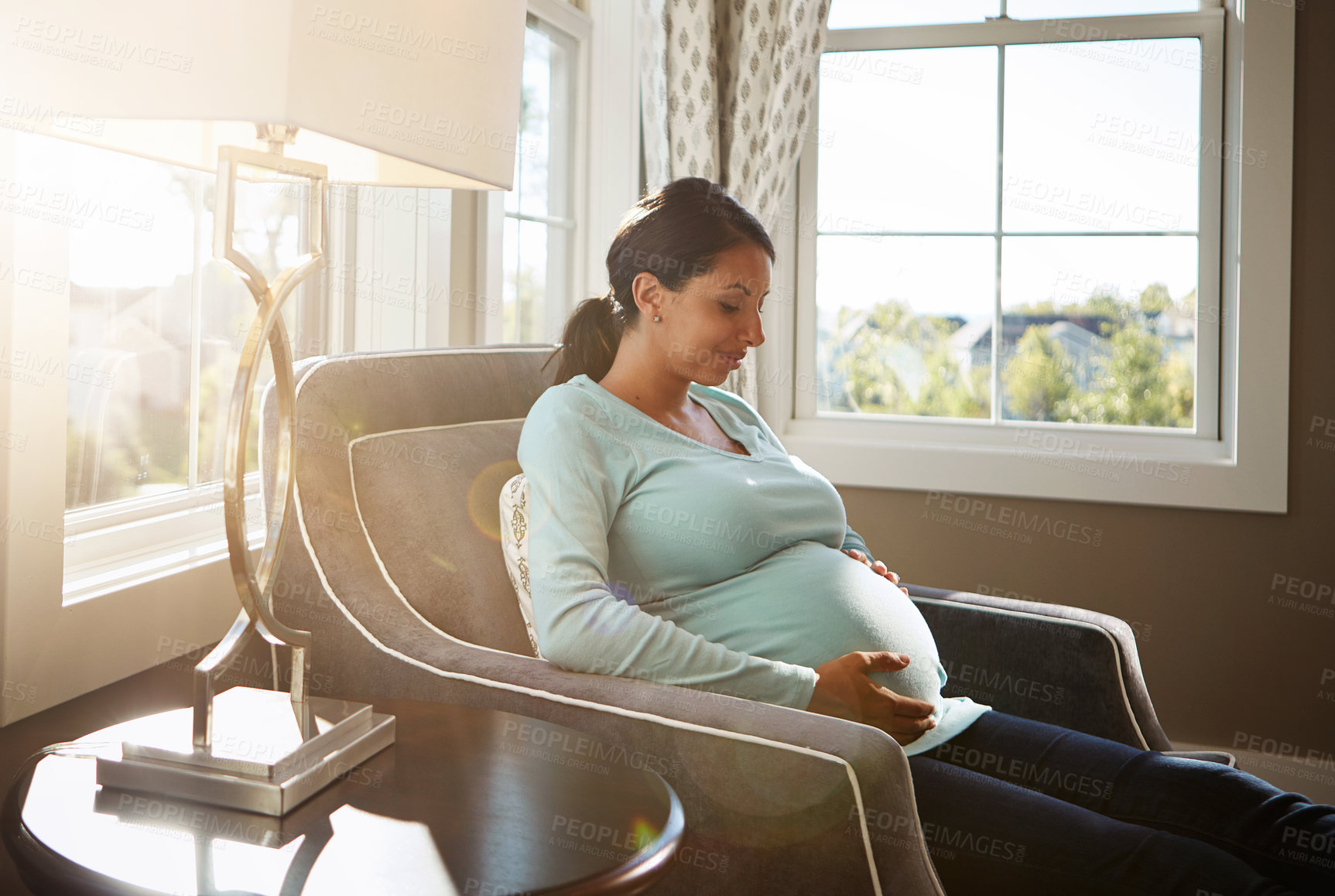 Buy stock photo Cropped shot of a pregnant woman sitting in her living room by herself