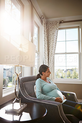 Buy stock photo Cropped shot of a pregnant woman sitting in her living room by herself