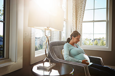 Buy stock photo Cropped shot of a pregnant woman sitting in her living room by herself