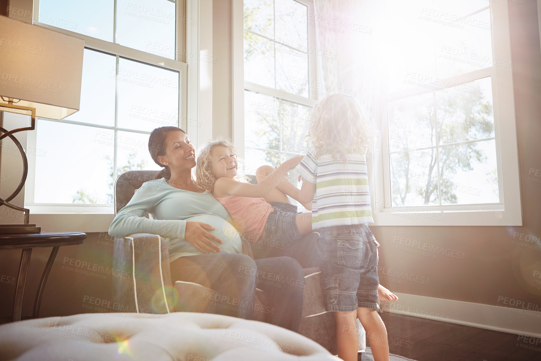 Buy stock photo Shot of a pregnant woman spending time with her children at home