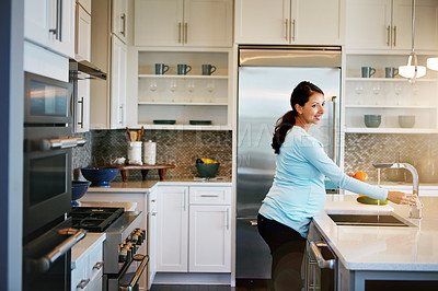 Buy stock photo Cropped shot of a pregnant woman washing vegetables in the kitchen sink