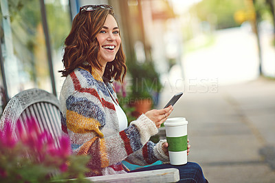 Buy stock photo Shot of a happy young woman using her cellphone while relaxing on a bench downtown