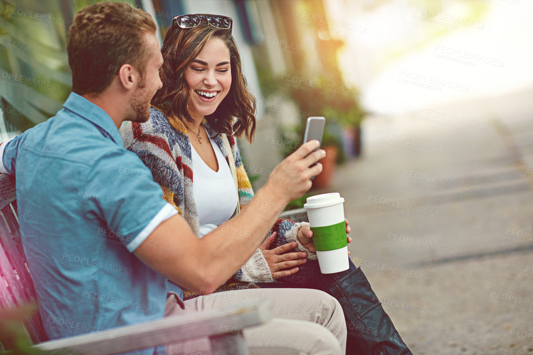 Buy stock photo Shot of a happy young couple using a smartphone together while spending the day downtown