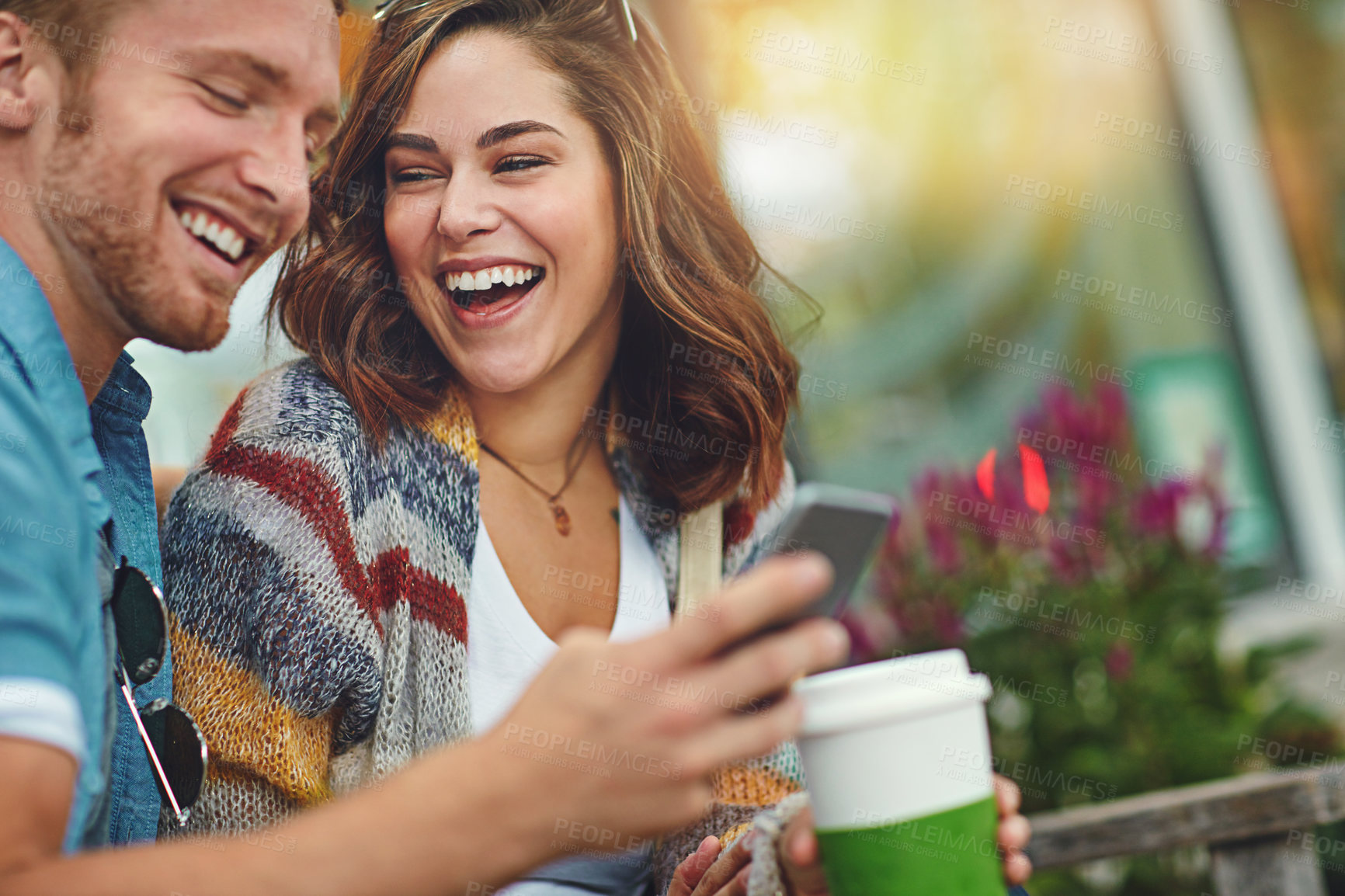 Buy stock photo Shot of a happy young couple using a smartphone together while spending the day downtown