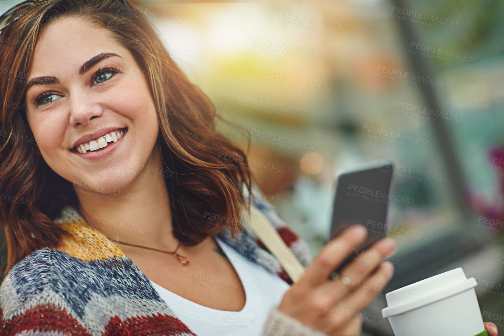 Buy stock photo Shot of a happy young woman using her cellphone while relaxing on a bench downtown