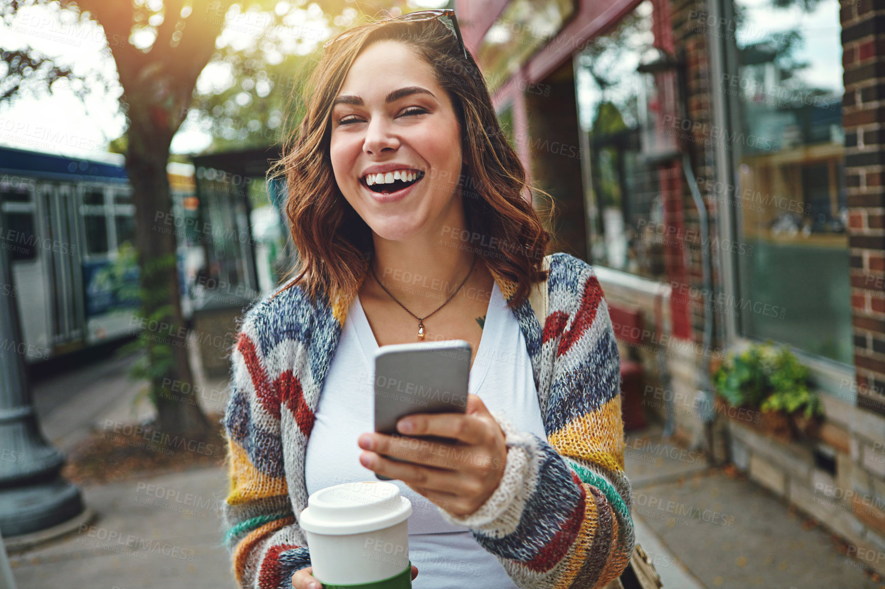 Buy stock photo Shot of a happy young woman using her cellphone while taking a walk downtown