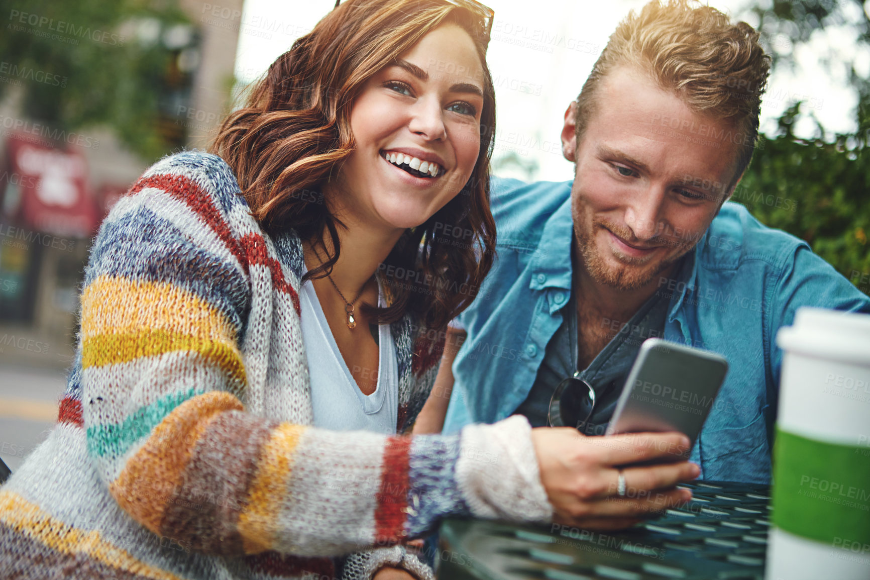 Buy stock photo Shot of a happy young couple using a smartphone together while spending the day downtown