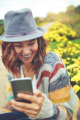 Buy stock photo Shot of an attractive young woman using a mobile phone during a spring day outdoors