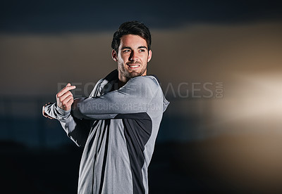 Buy stock photo Shot of a young man stretching outside before his run