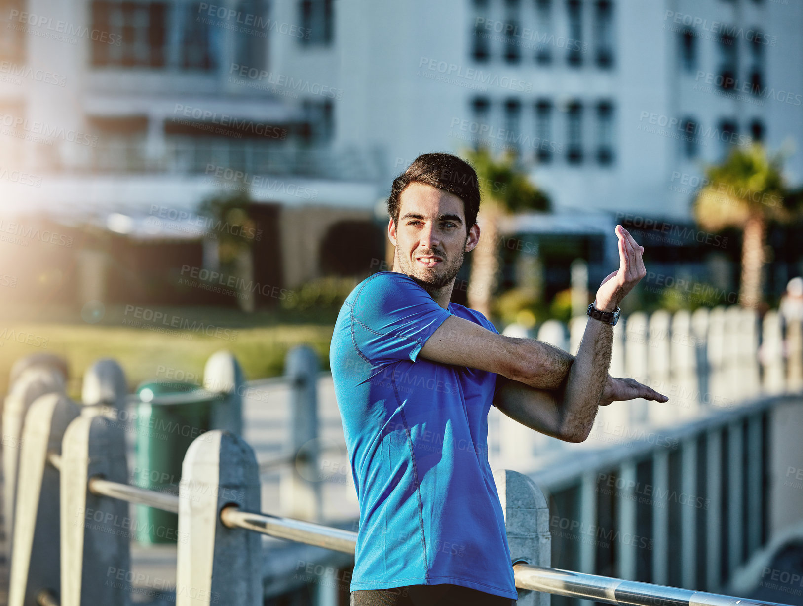 Buy stock photo Shot of a young man stretching outside before his run
