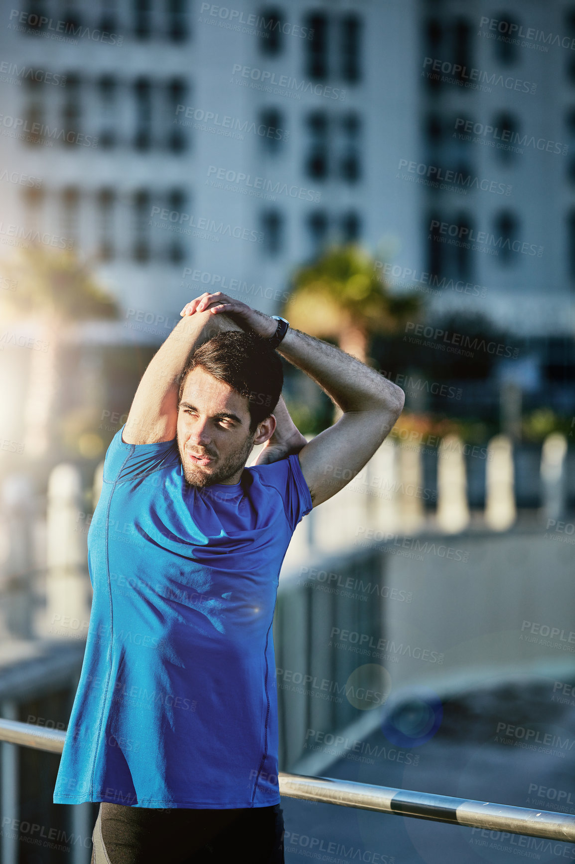 Buy stock photo Shot of a young man stretching outside before his run