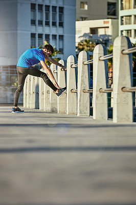 Buy stock photo Shot of a young man stretching outside before his run