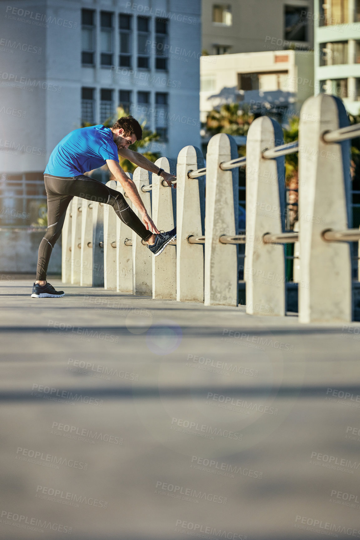 Buy stock photo Shot of a young man stretching outside before his run