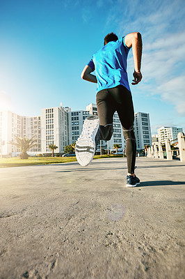 Buy stock photo Rearview shot of a sporty young man out for a run