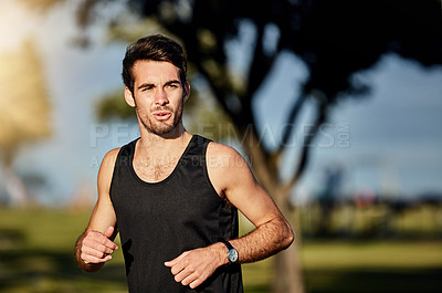 Buy stock photo Shot of a young man out for a jog in a park