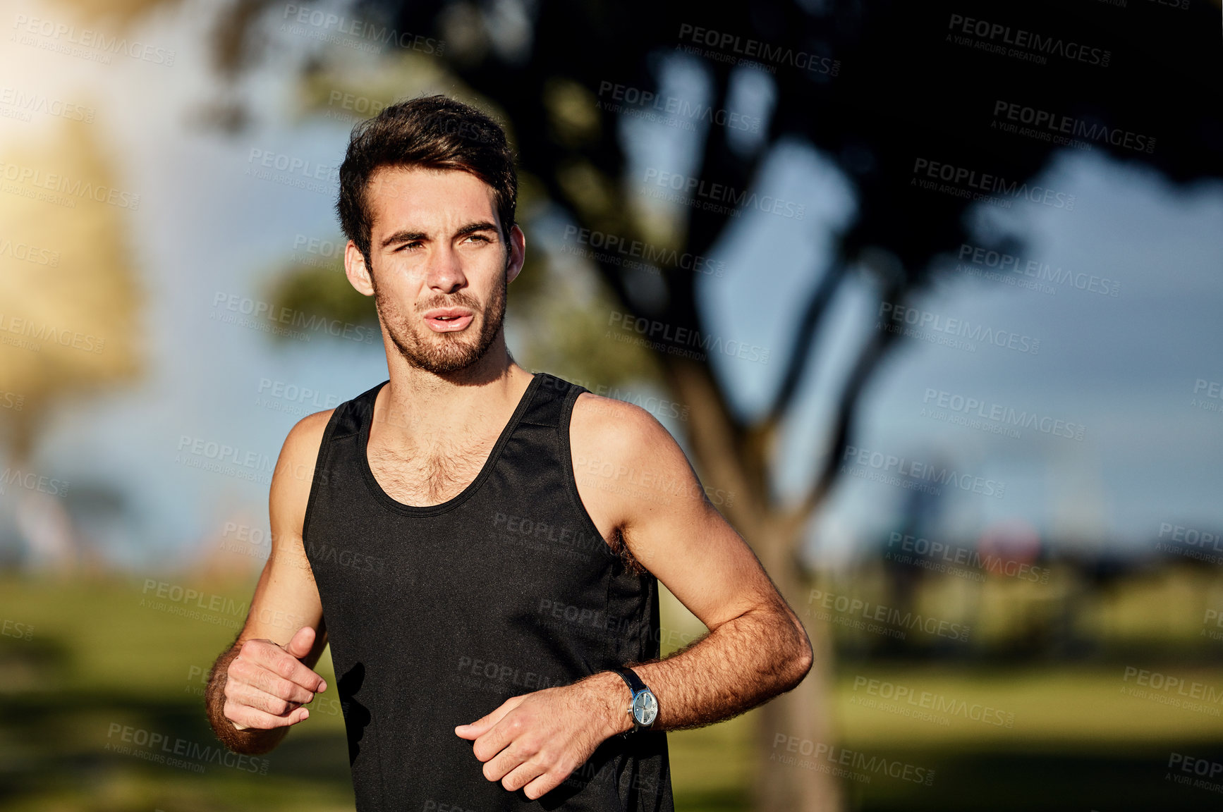 Buy stock photo Shot of a young man out for a jog in a park