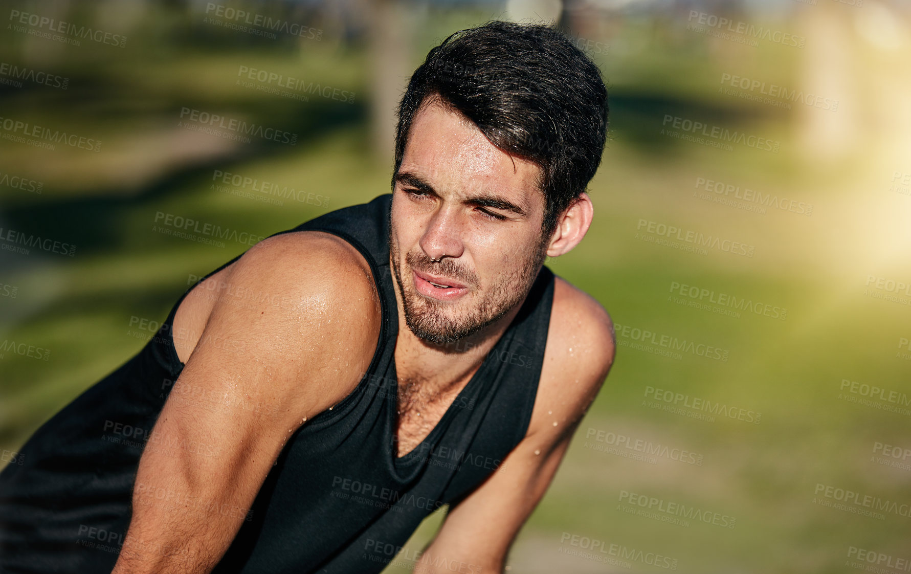 Buy stock photo Shot of a young jogger resting while out for a run in a park