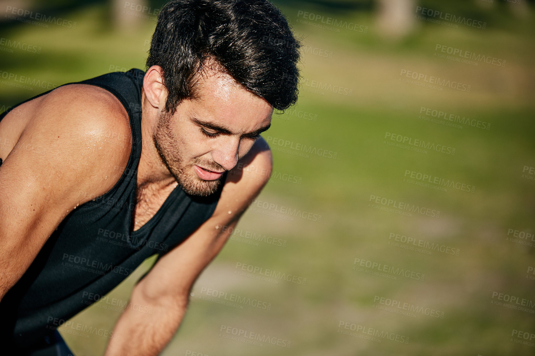 Buy stock photo Shot of a young jogger resting while out for a run in a park