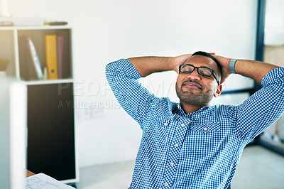 Buy stock photo Shot of a handsome young man sitting with his hands behind his head in the office