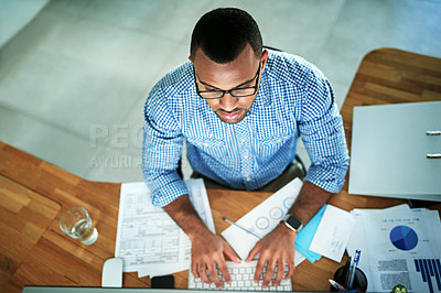 Buy stock photo High angle shot of a handsome young businessman working in his office