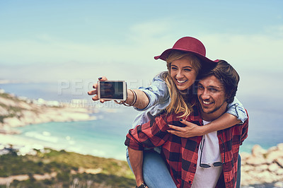 Buy stock photo Shot of an affectionate young couple taking selfies while hiking in the mountains