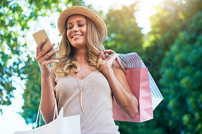 Buy stock photo Shot of an attractive young woman checking her text messages while shopping