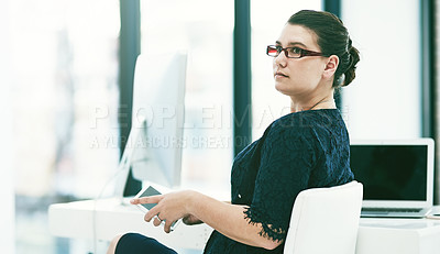 Buy stock photo Shot of a thoughtful young businesswoman working at her desk in an office